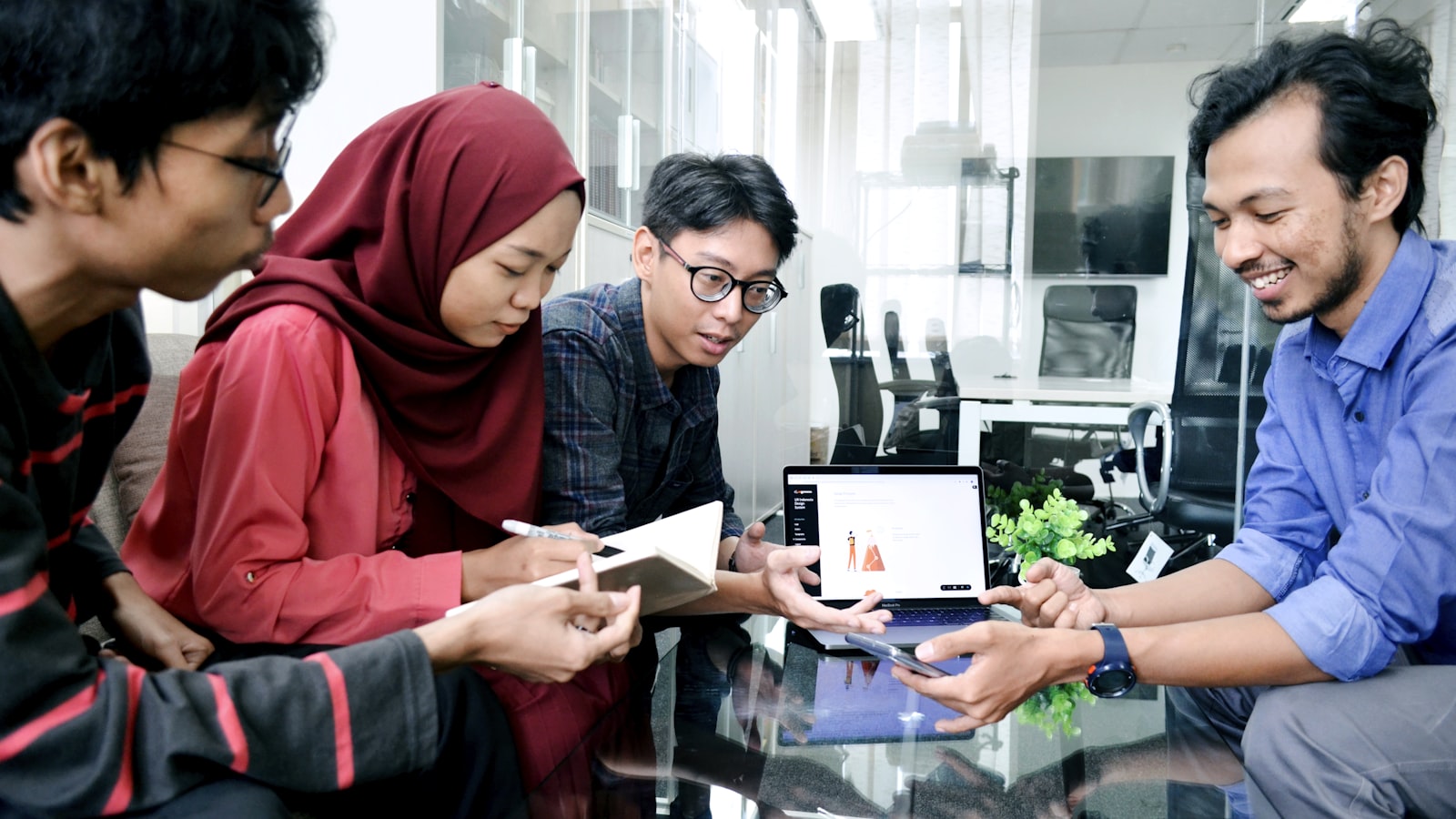 A small team gathered around a laptop reviewing work together in a studio