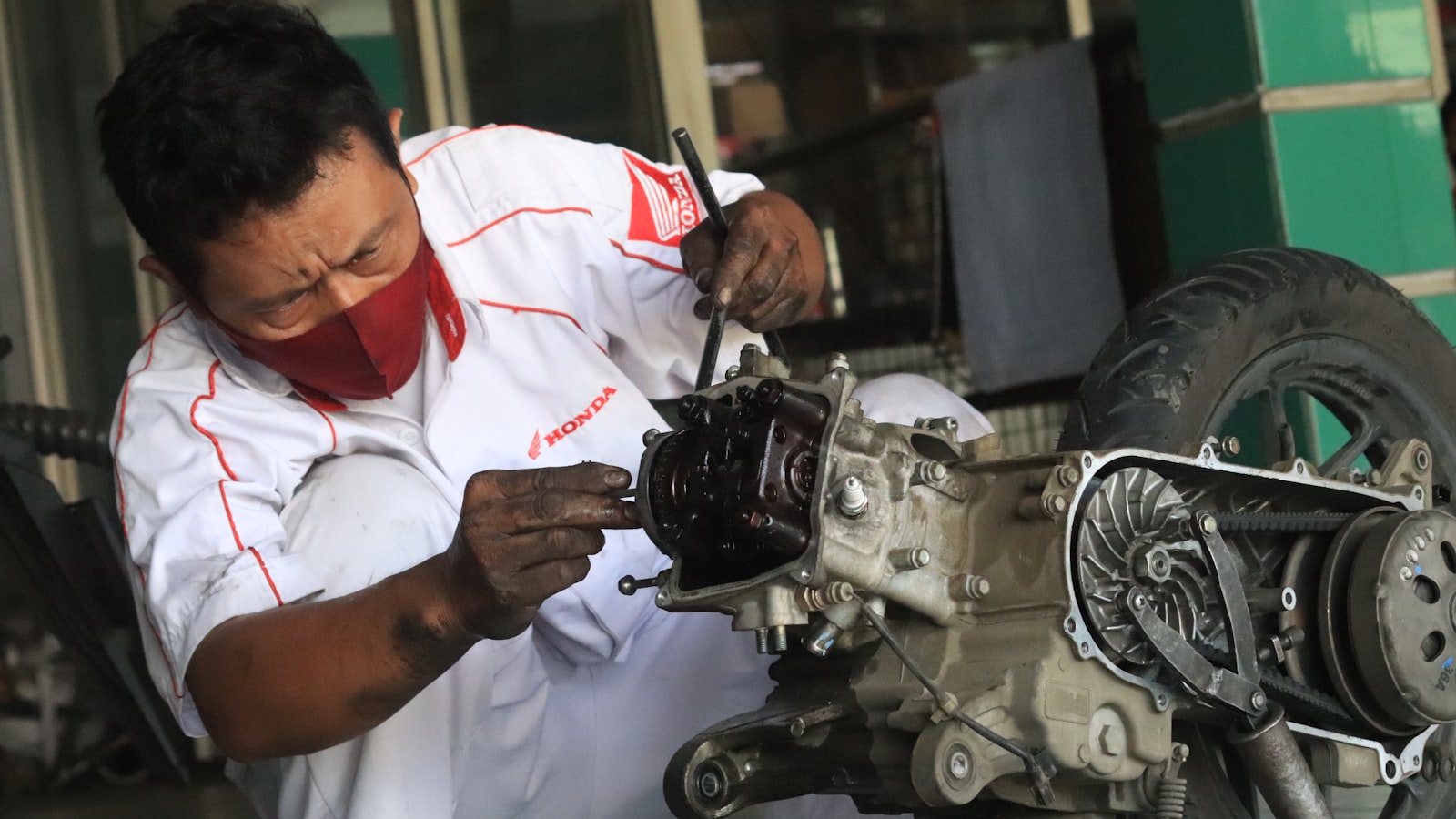 A mechanic repairing a motorbike engine on a workbench in a workshop